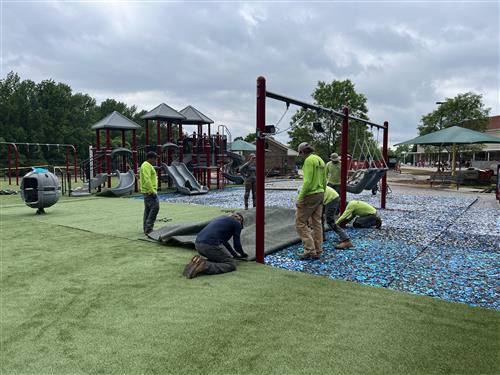 workmen laying turf on playground